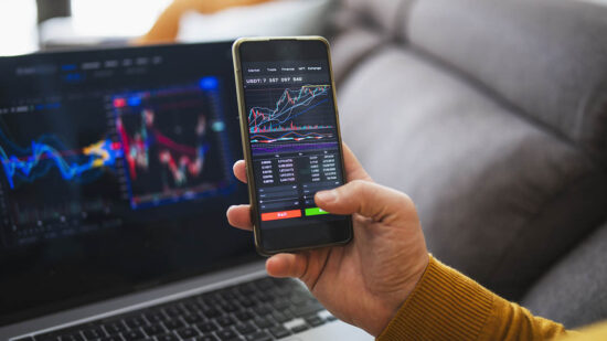 Man buying cryptocurrency at home via laptop and phone.