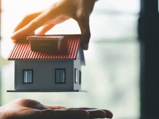 Business woman holding home miniature in office bureau. insurance protective hand over house for protection and care, Concept of home and real estate Property insurance.