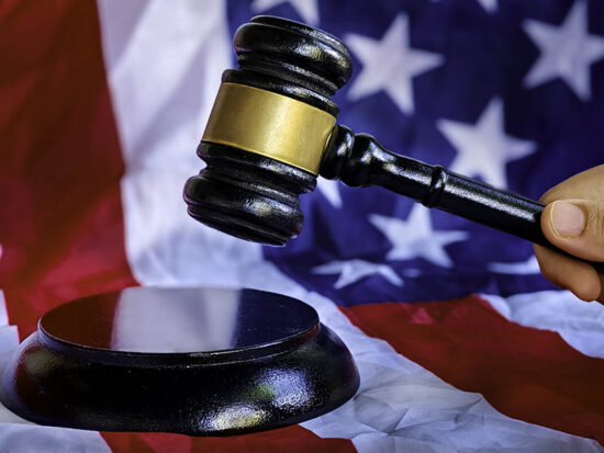 A hand holding gavel with background of usa flag.
