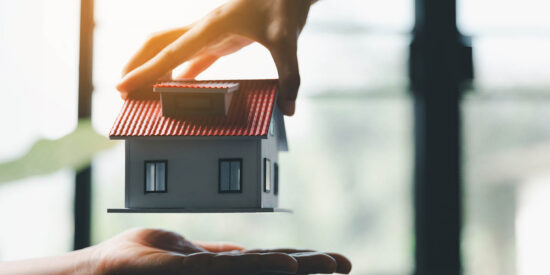 Business woman holding home miniature in office bureau. insurance protective hand over house for protection and care, Concept of home and real estate Property insurance.