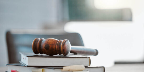 Justice, gavel and law books on table in office for court trial, legislation or fair constitution by judicial system. Firm, closeup and legal hammer by information for corporate case in workplace.