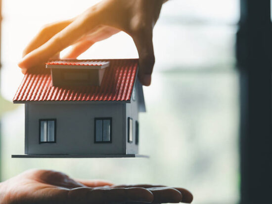Business woman holding home miniature in office bureau. insurance protective hand over house for protection and care, Concept of home and real estate Property insurance.