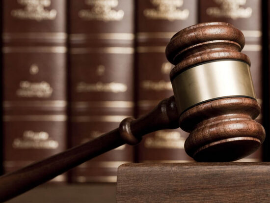 Gavel on wooden desk with books as background
